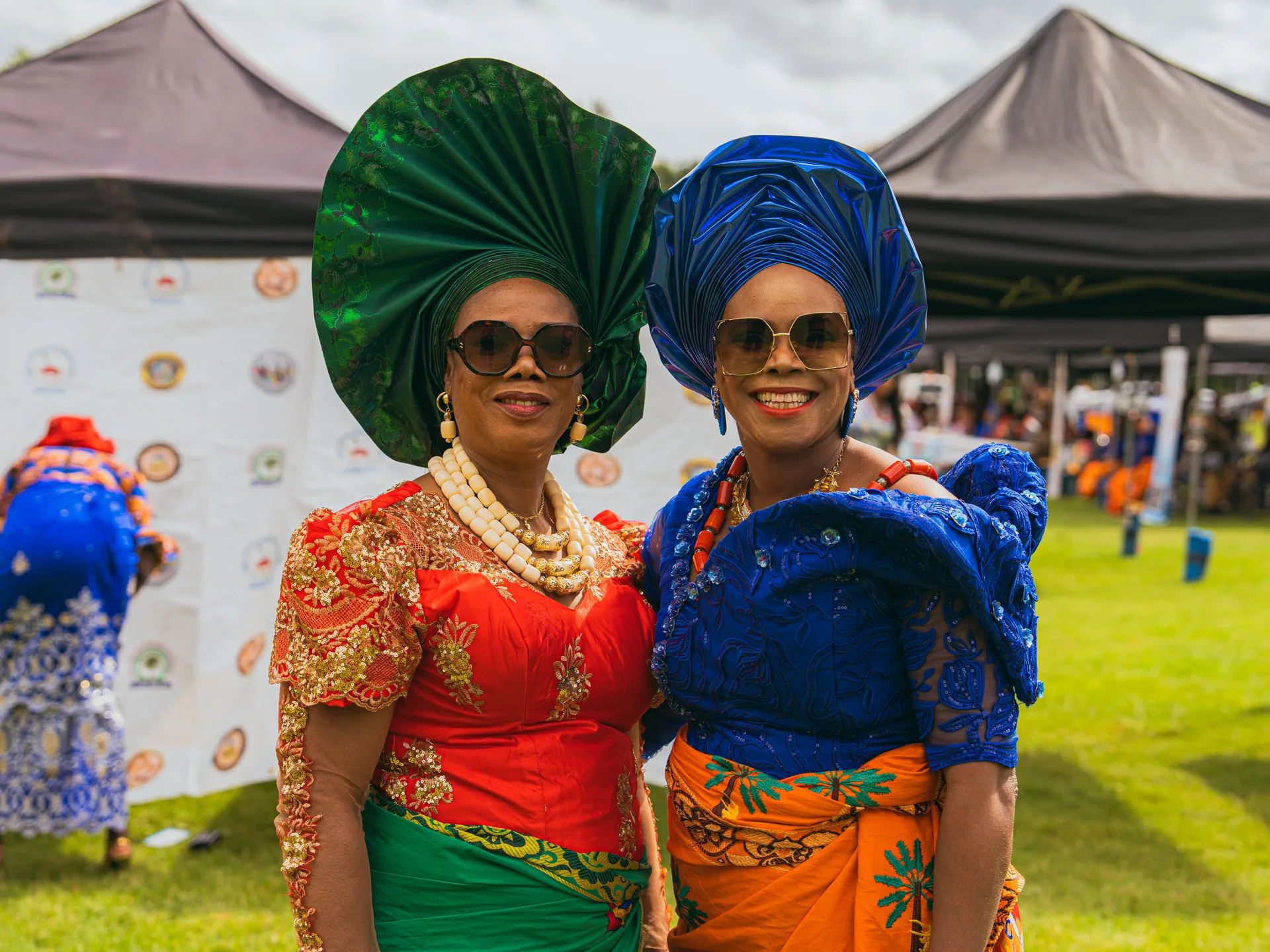 Two women in green and blue gele with coral beads