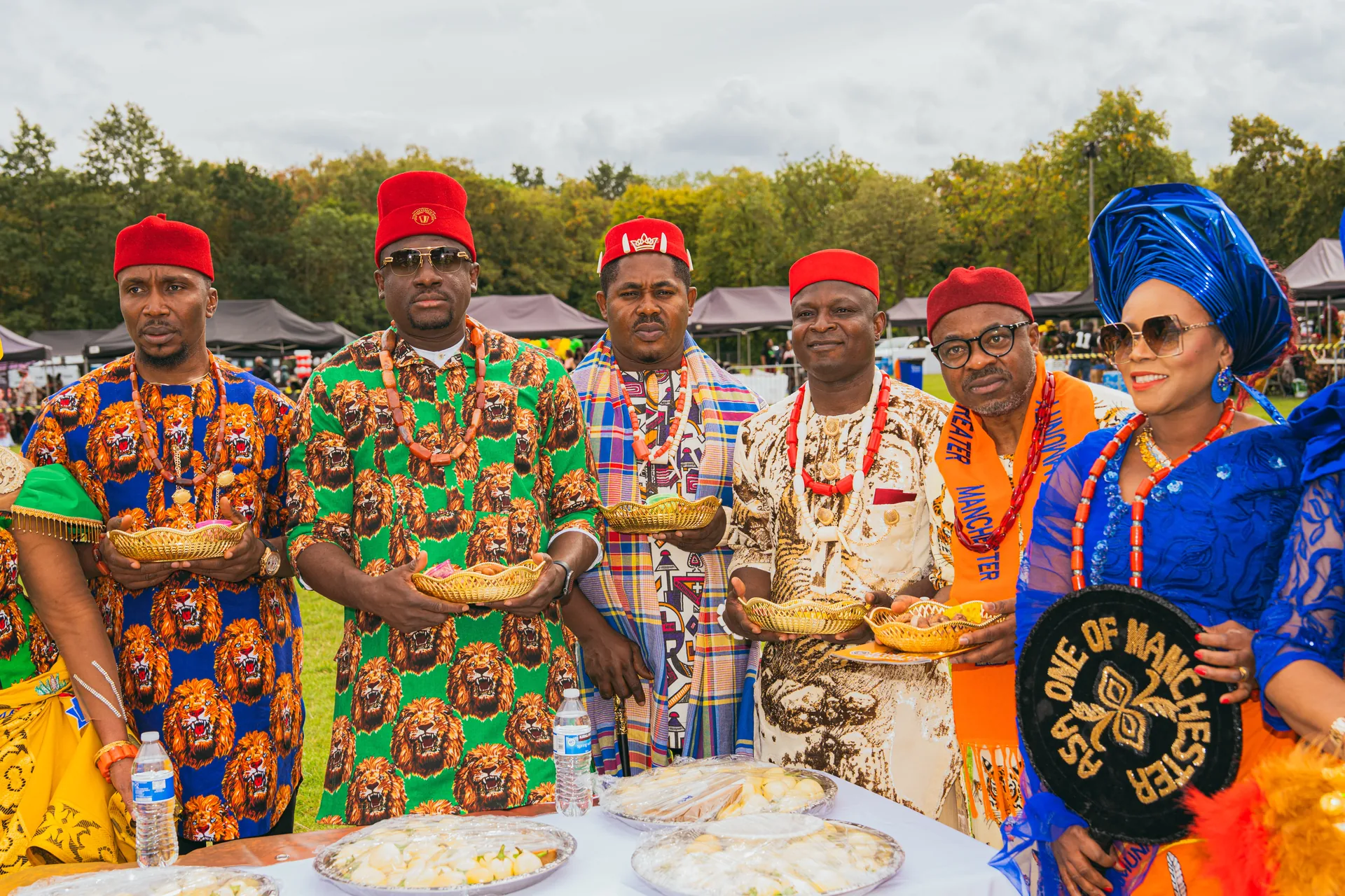 Elders holding gold baskets of yam at a table